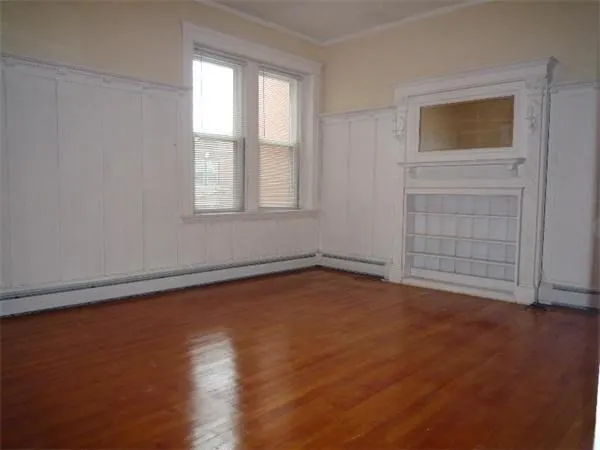 an empty room with wooden floor and windows with curtains