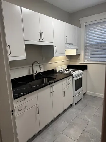 a kitchen with granite countertop white cabinets and a stove