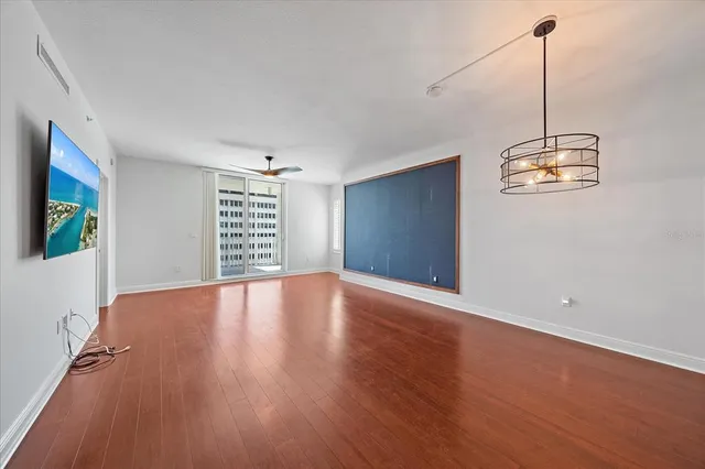 a view of empty room with wooden floor and fan