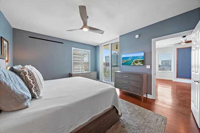 a spacious bedroom with a bed and a dresser with wooden floor