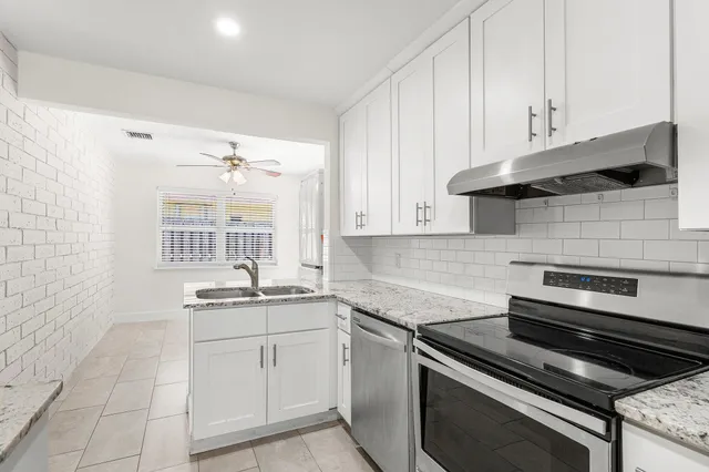 a kitchen with white cabinets appliances and a sink