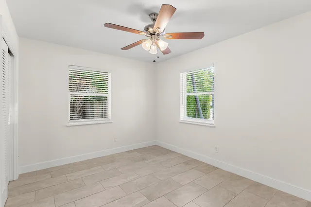 an empty room with windows and ceiling fan