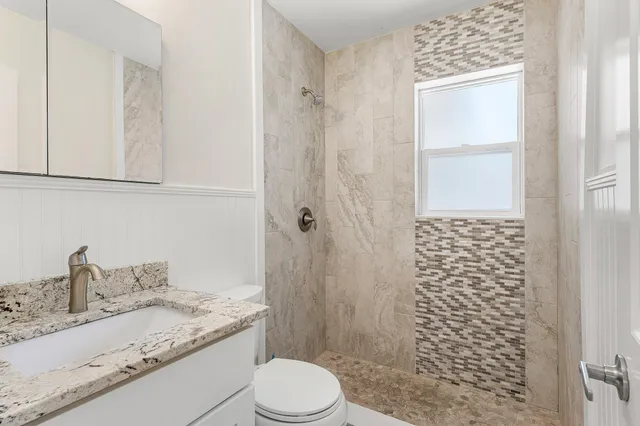 a bathroom with a granite countertop sink toilet and shower