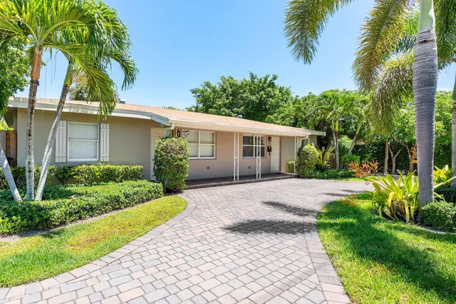 a view of a house with a yard and palm trees