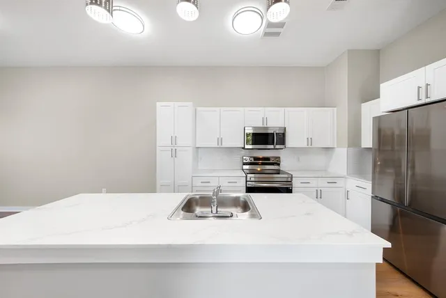 a view of a kitchen with kitchen island wooden floor center island and stainless steel appliances