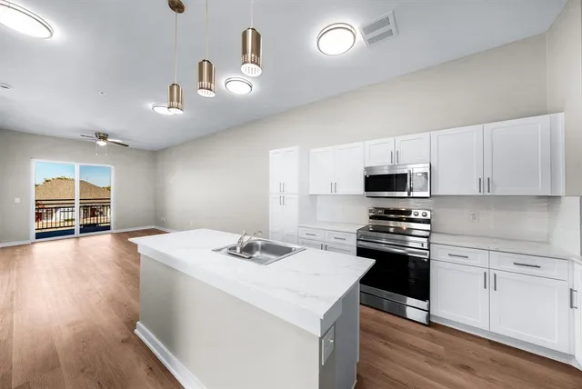 a kitchen with a sink a counter top space stainless steel appliances and cabinets