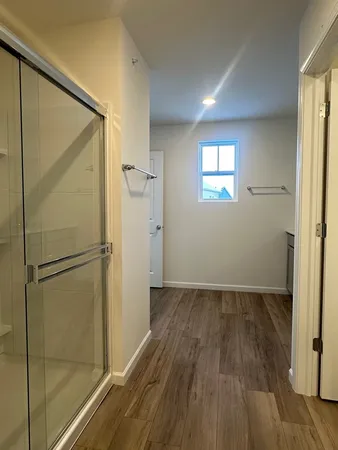 a view of an empty room with wooden floor and a window