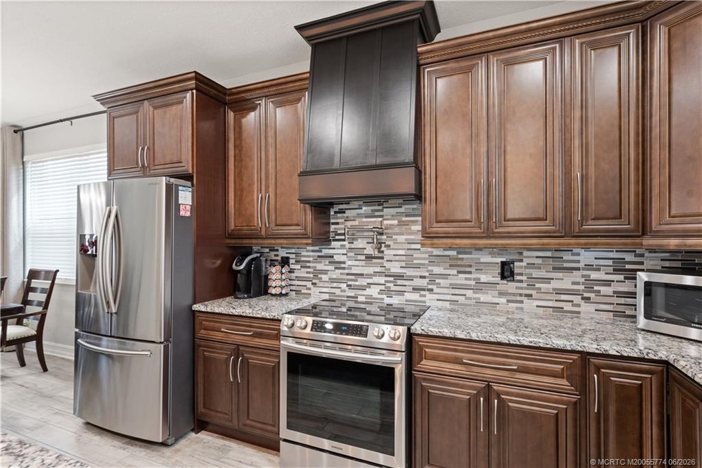 1268 Southeast Kirk Street Stuart, FL 34997 - Photo 24 of 63 a kitchen with stainless steel appliances granite countertop a refrigerator and a sink