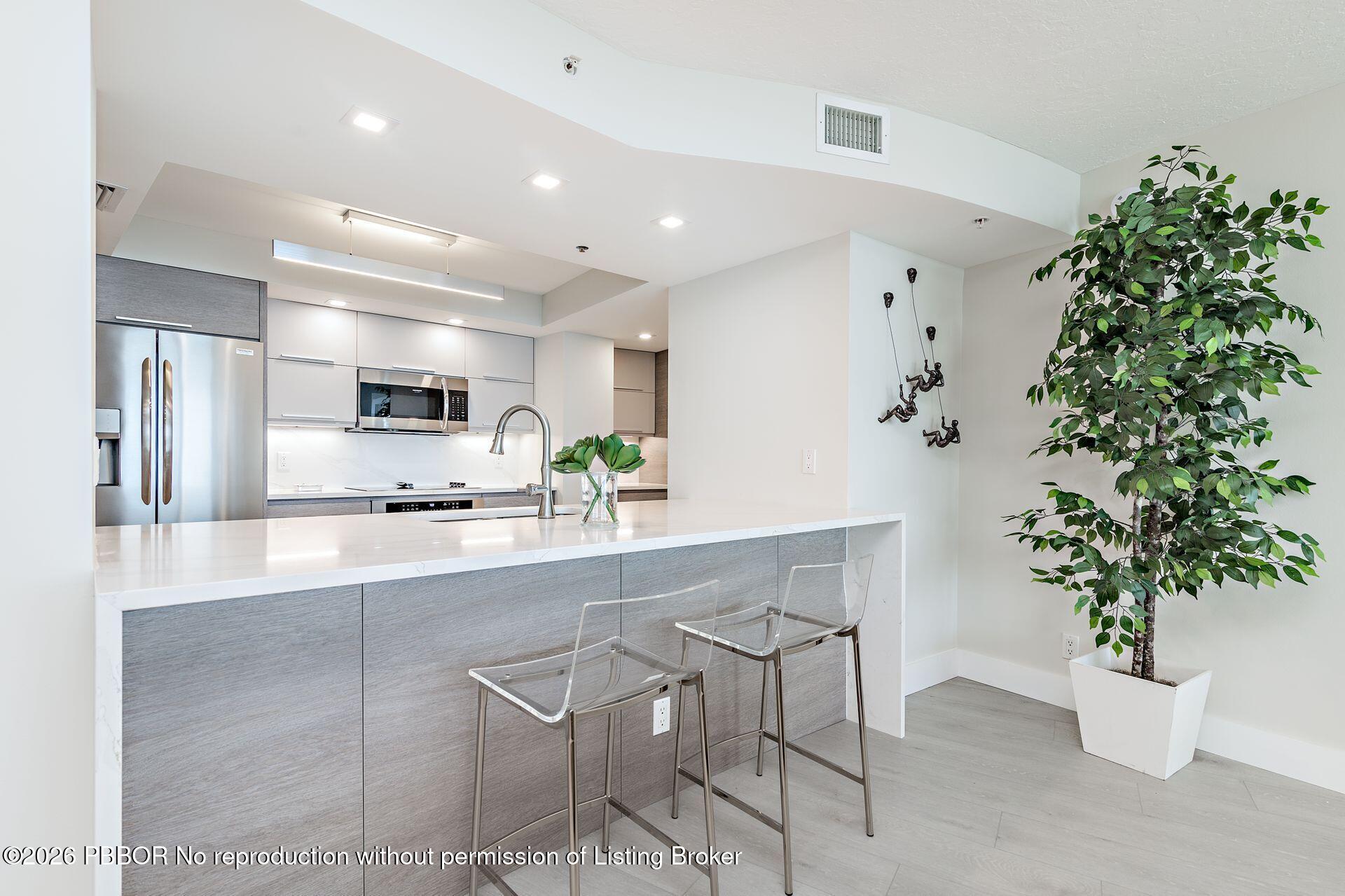 3000 North Ocean Drive, Unit 32E Riviera Beach, FL 33404 - Photo 21 of 36 a large kitchen with stainless steel appliances a large tree in it