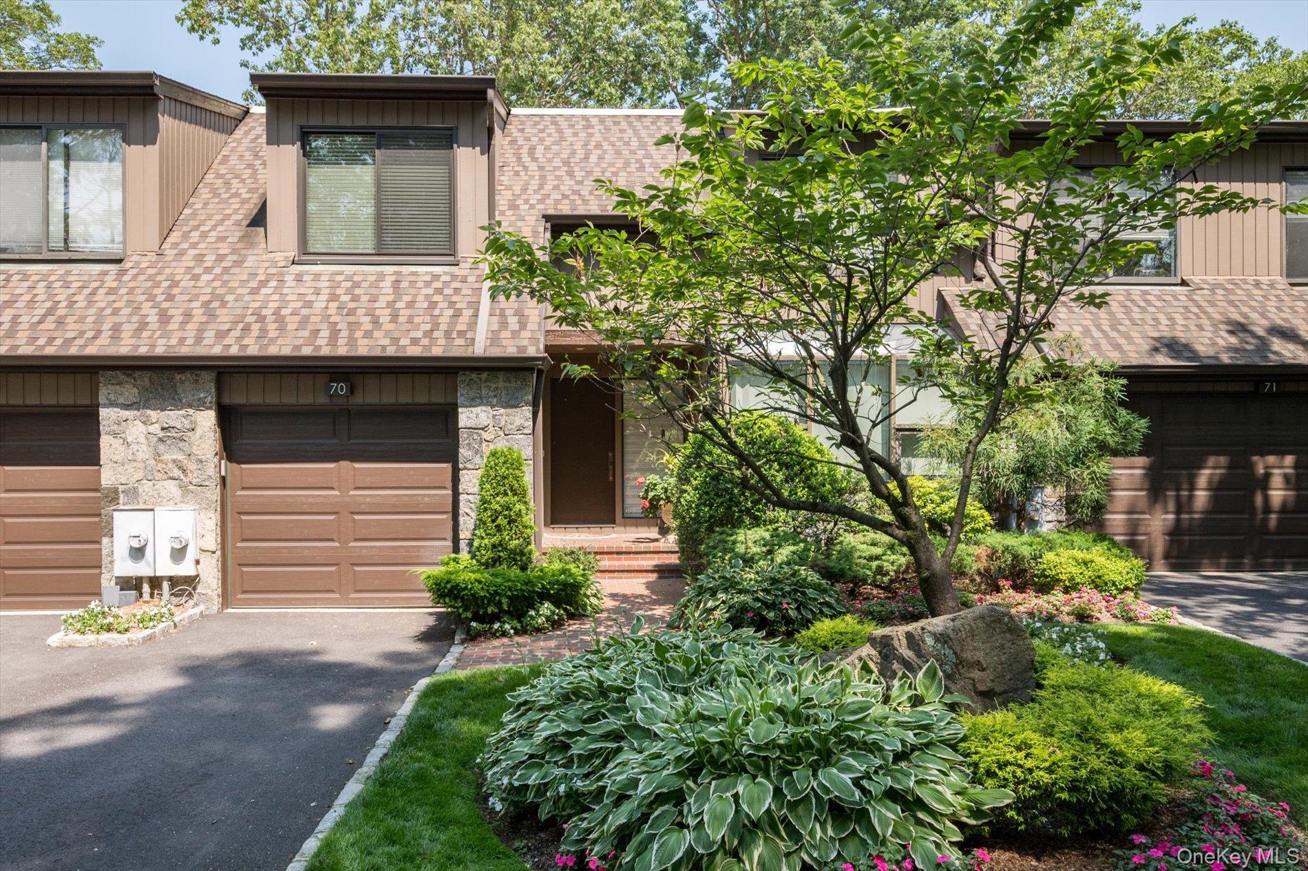View of front of property featuring roof with shingles, driveway, board and batten siding, and stone siding