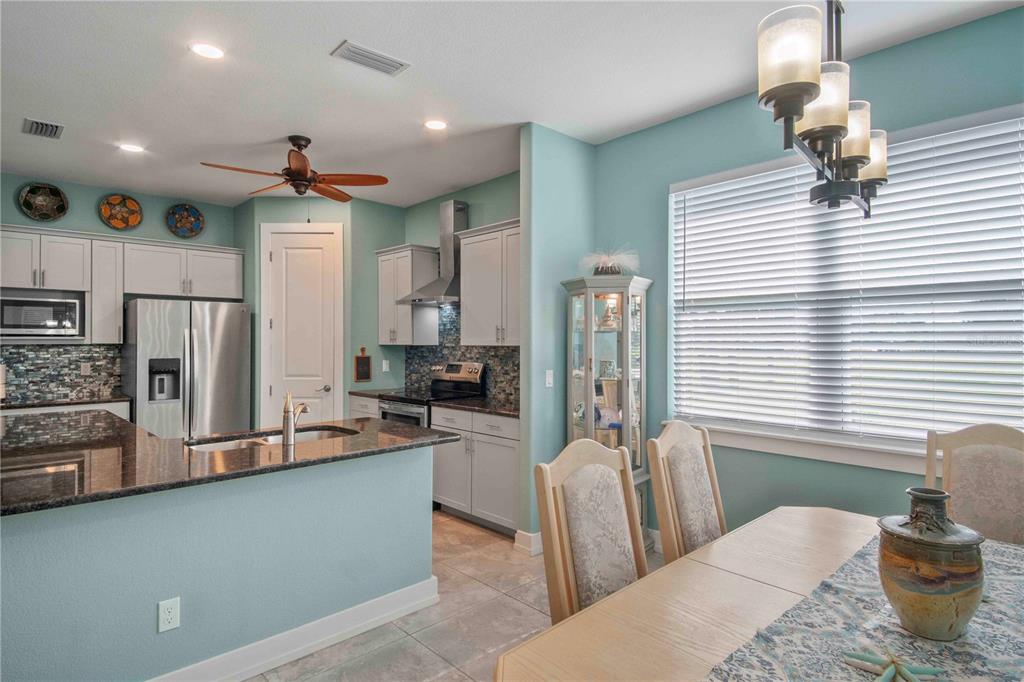 114 Venice Road Rotonda West, FL 33947 - Photo 29 of 88 a kitchen with stainless steel appliances kitchen island granite countertop a refrigerator a sink dishwasher a stove and a dining table with wooden floor