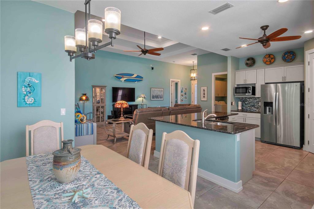 114 Venice Road Rotonda West, FL 33947 - Photo 34 of 88 a kitchen with stainless steel appliances kitchen island granite countertop a refrigerator a stove top oven a dining table and chairs with wooden floor