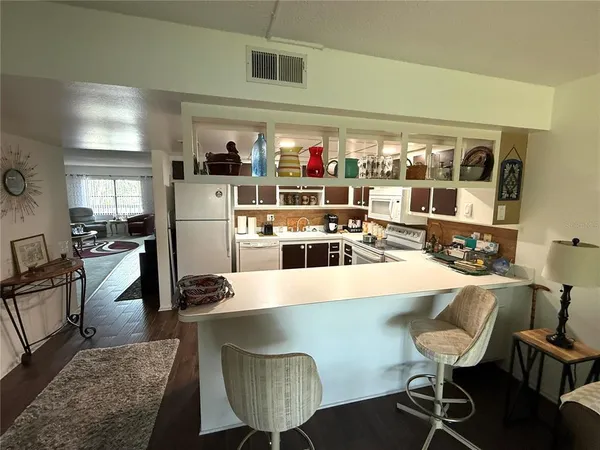 a kitchen with stainless steel appliances granite countertop a table chairs and a refrigerator