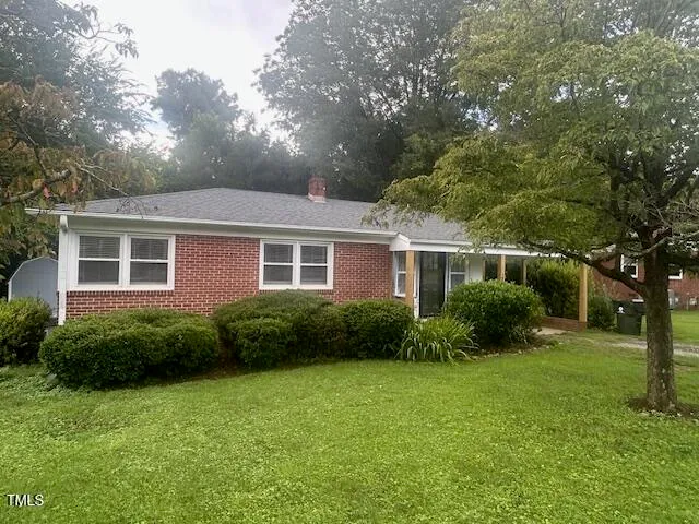 a view of a house next to a big yard and large trees