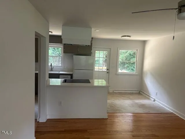 a living room with stainless steel appliances a refrigerator and a window
