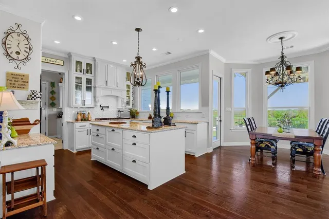 a large white kitchen with lots of counter space and chandelier