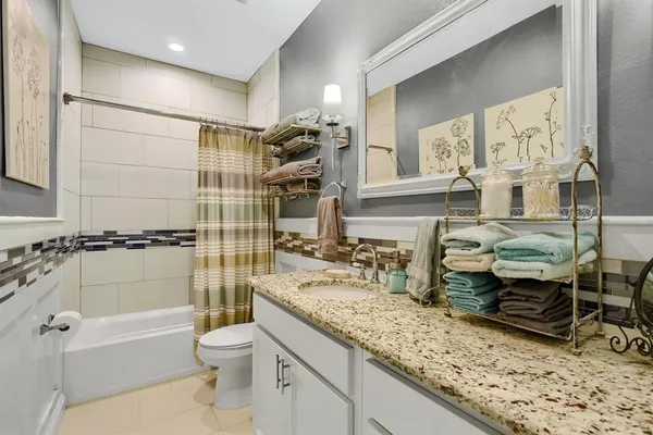 a bathroom with a granite countertop sink toilet mirror and bathtub