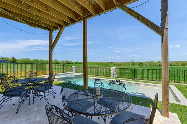 a view of a patio with dining table chairs and a backyard