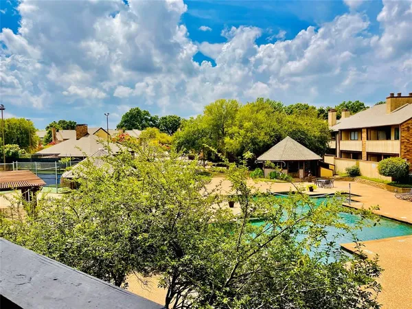 a view of a swimming pool with lawn chairs under an umbrella