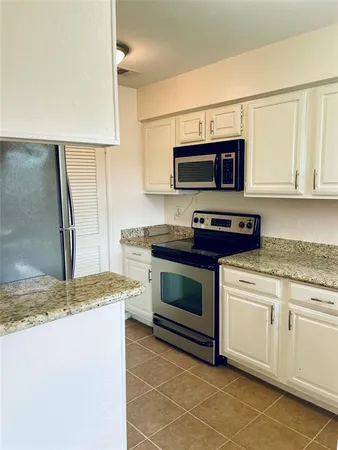 a kitchen with granite countertop a sink stainless steel appliances and white cabinets