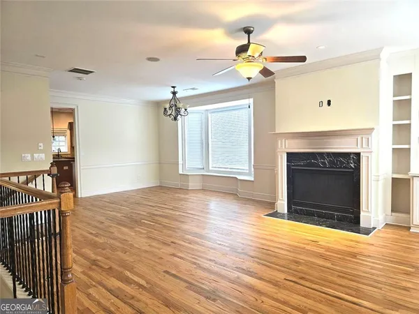a view of an empty room with wooden floor and a fireplace