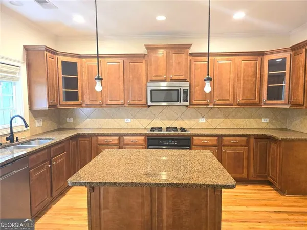 a kitchen with stainless steel appliances granite countertop a sink a stove and a wooden cabinets