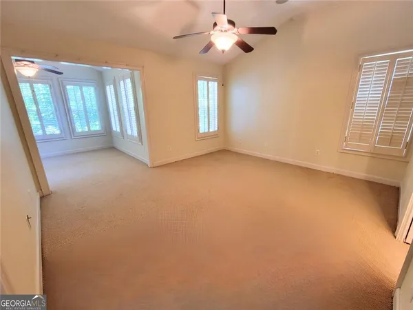 an empty room with windows and fan