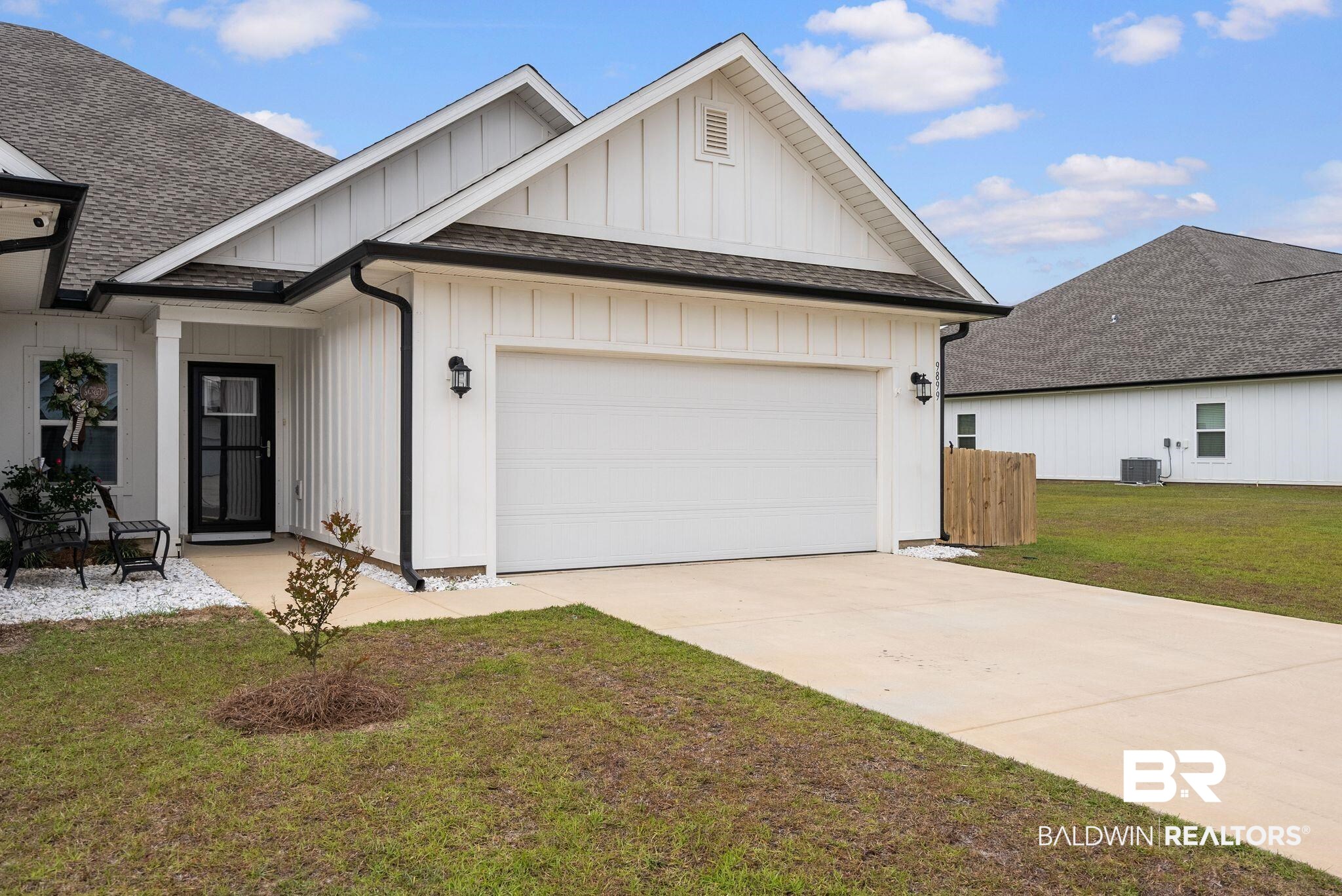 9899 Willet Way Foley, AL 36535 - Photo 1 of 37 White board-and-batten exterior featuring a two-car garage, black front door, dark gutters, and a concrete driveway