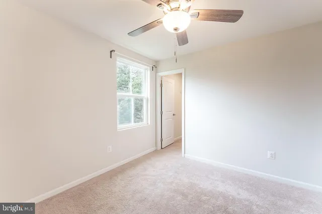 an empty room with a chandelier fan and closet