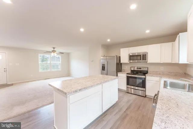 a kitchen with stainless steel appliances granite countertop a stove top oven a sink dishwasher and a refrigerator with wooden floor