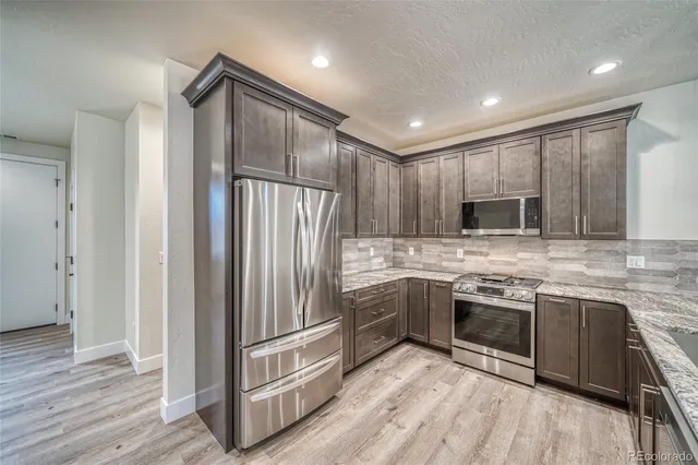 a kitchen with stainless steel appliances granite countertop a refrigerator and a stove top oven