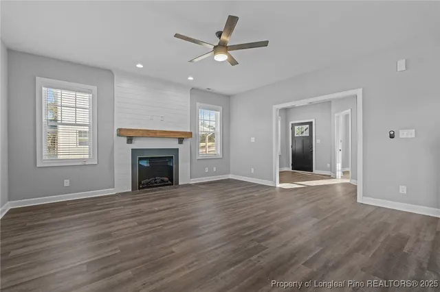 a view of an empty room with wooden floor fireplace and a window