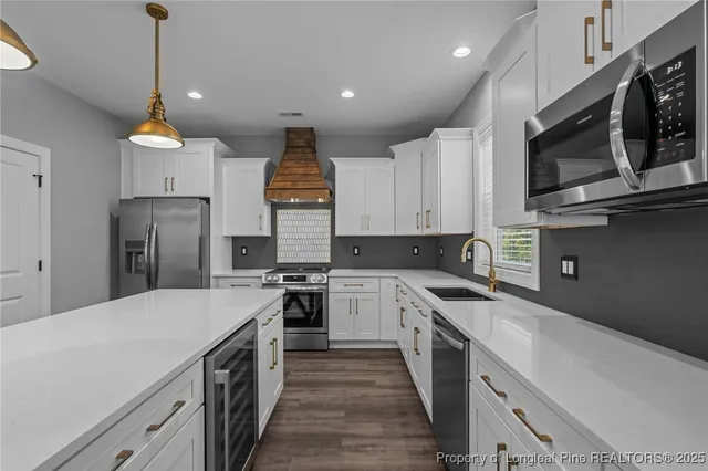 a kitchen with stainless steel appliances a sink a stove top oven a refrigerator cabinets and a window