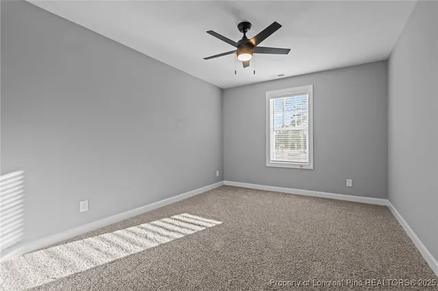 an empty room with windows and a ceiling fan