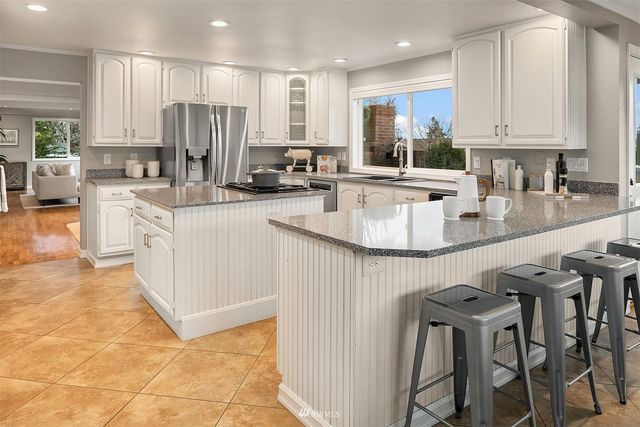 a kitchen with stainless steel appliances granite countertop a table chairs sink and cabinets