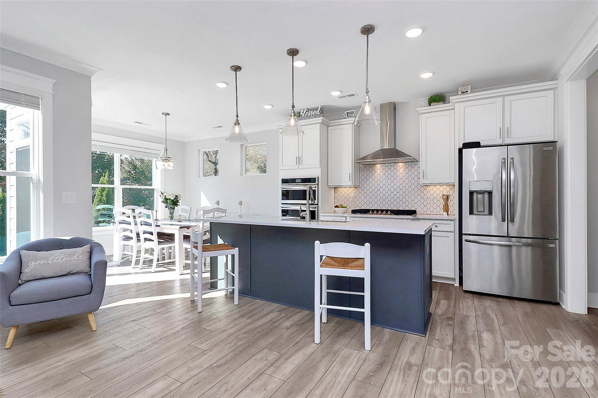 4030 Belle Landing Road, Unit 7 Charlotte, NC 28270 - Photo 2 of 24 a kitchen with kitchen island a refrigerator a stove a dining table and chairs with wooden floor