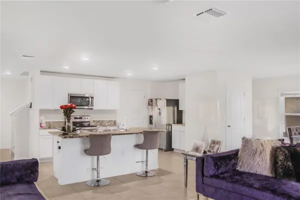 a kitchen with stainless steel appliances kitchen island granite countertop a sink and a refrigerator