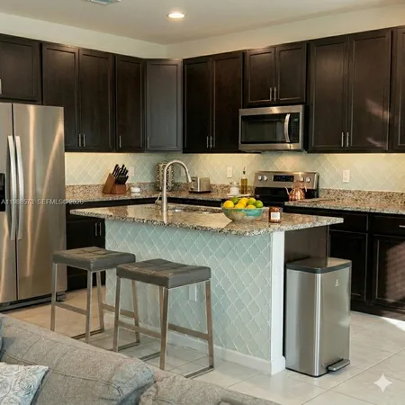 a kitchen with stainless steel appliances a stove a sink a microwave a refrigerator and cabinets