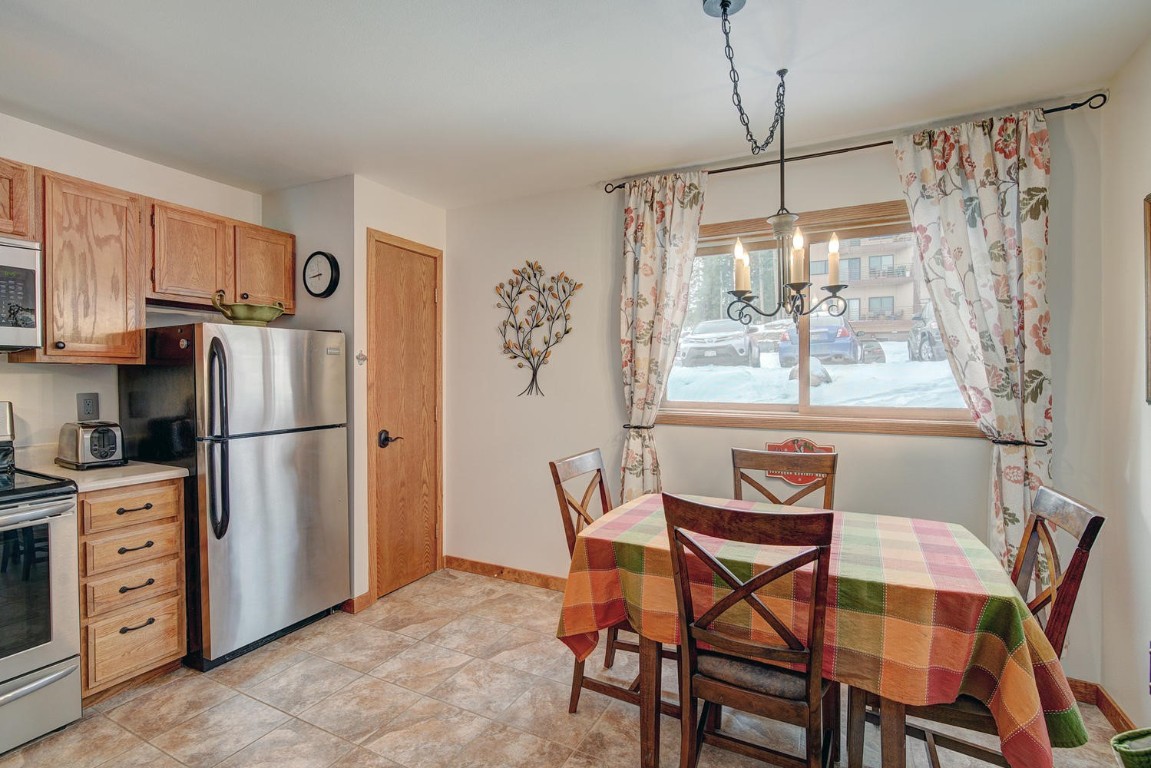 10000 Ryan Gulch Road, Unit 109 Silverthorne, CO 80498 - Photo 6 of 25 a kitchen with stainless steel appliances a refrigerator a stove a dining table and chairs with wooden floor