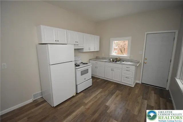 a kitchen with a white cabinets a sink a window and wooden floor