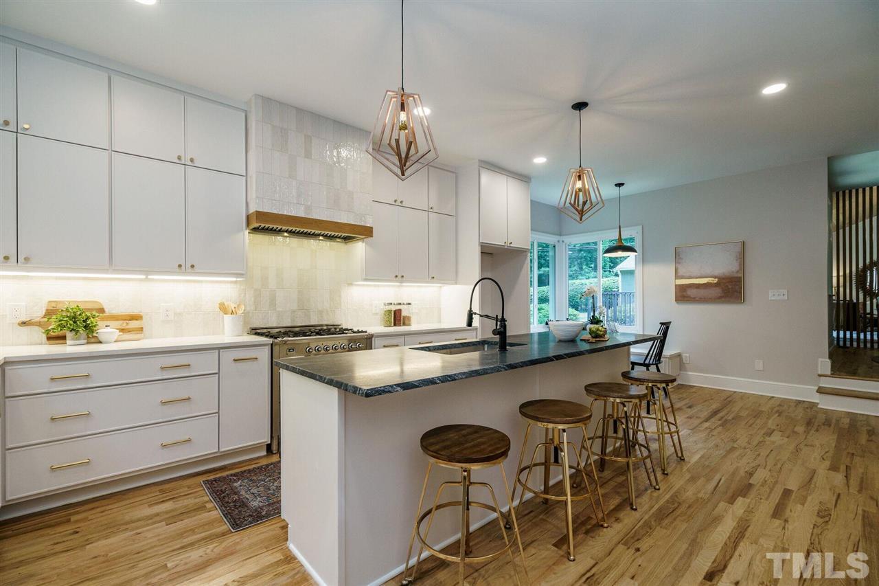 2005 Banbury Road Raleigh, NC 27608 - Photo 10 of 30 Large Kitchen features a gas-burning Fireplace, a nearly 9' Island with Granite Countertops, Quartz Countertops, Italian Gas Range, Lots of prep and Serving spaces. A walk-in Pantry is located behind the Fireplace. Note the beautiful Hardwood floors.