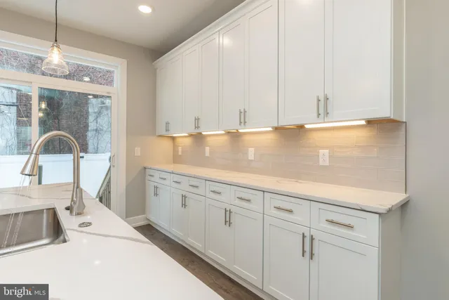 a view of a kitchen counter space a sink wooden floor and a window