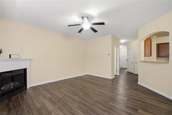 a view of an empty room with wooden floor a fireplace and a window