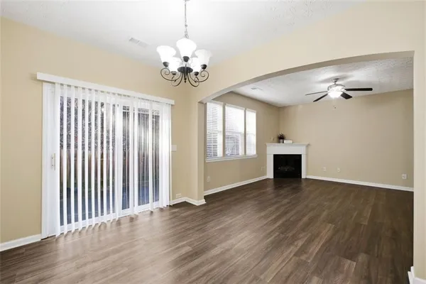 an empty room with wooden floor chandelier and windows