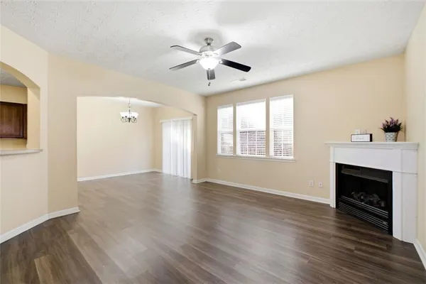 a view of an empty room with wooden floor fireplace and a window