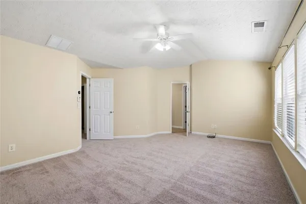 an empty room with windows and chandelier fan