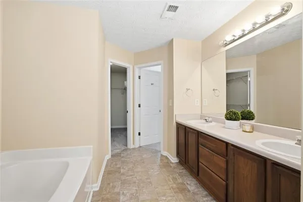 a spacious bathroom with a tub sink and mirror