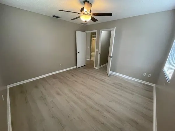 an empty room with closet and a chandelier fan