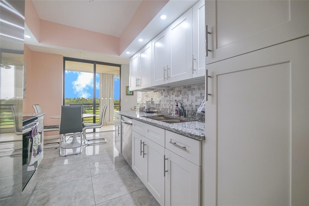 7300 Radice Court, Unit 404 Lauderhill, FL 33319 - Photo 12 of 85 a kitchen with granite countertop a sink appliances cabinets and furniture