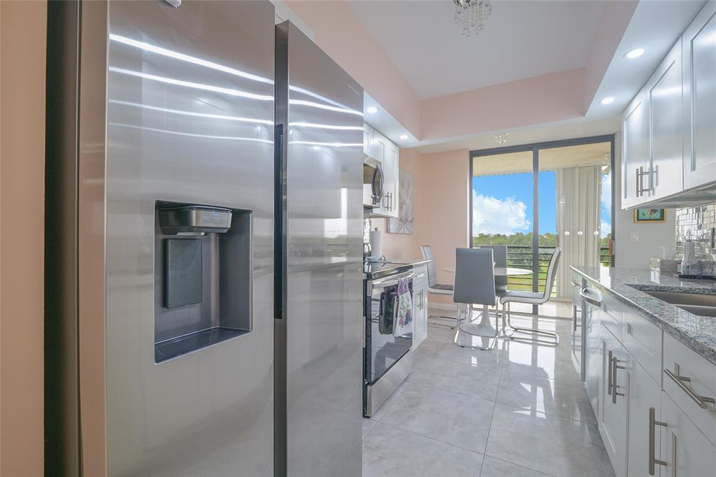 7300 Radice Court, Unit 404 Lauderhill, FL 33319 - Photo 13 of 85 a kitchen with granite countertop a refrigerator and chairs